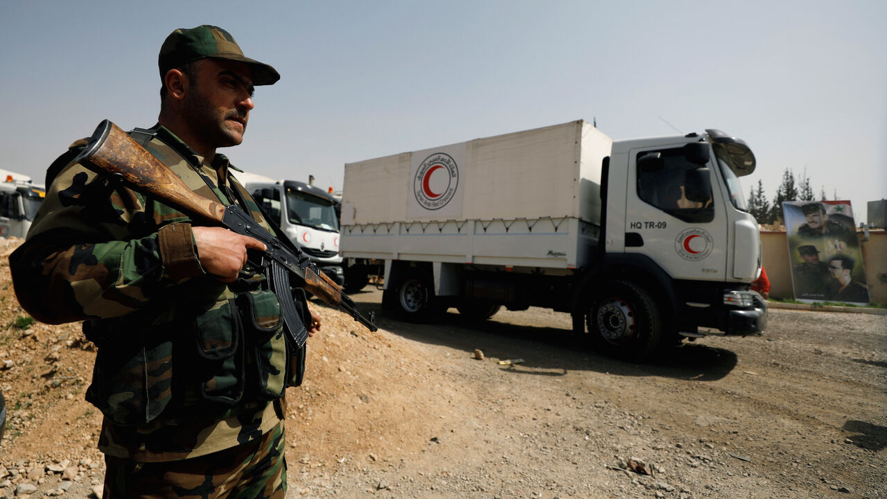 MIDEAST-CRISIS/SYRIA-GHOUTA A Syrian army soldier is seen securing Syrian Arab Red Crescent trucks carrying aid at the entrance of Wafideen camp in Damascus, Syria March 5, 2018. REUTERS/Omar Sanadiki - RC12D8D4A5F0