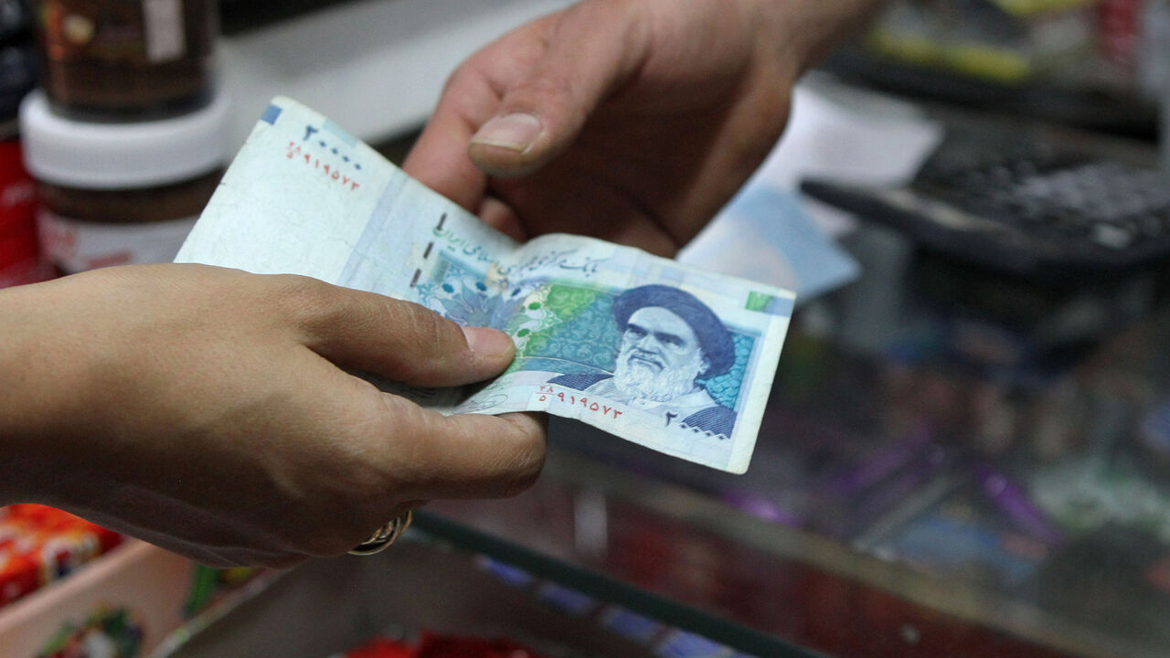 Nic6138021 An Iranian woman pays a 20000 rial banknote (around 70 US Cent), bearing a portrait of Iran's late founder of islamic Republic Ayatollah Ruhollah Khomeini, to a grocer in Tehran on September 30, 2012. Iran's currency, the rial has lost over 60 percent of its value since the end of last year, as draconian Western economic sanctions take effect that has spurred already high inflation to even greater heights, with food costs soaring more than 50 percent. AFP PHOTO/ATTA KENARE (Photo credit should read A