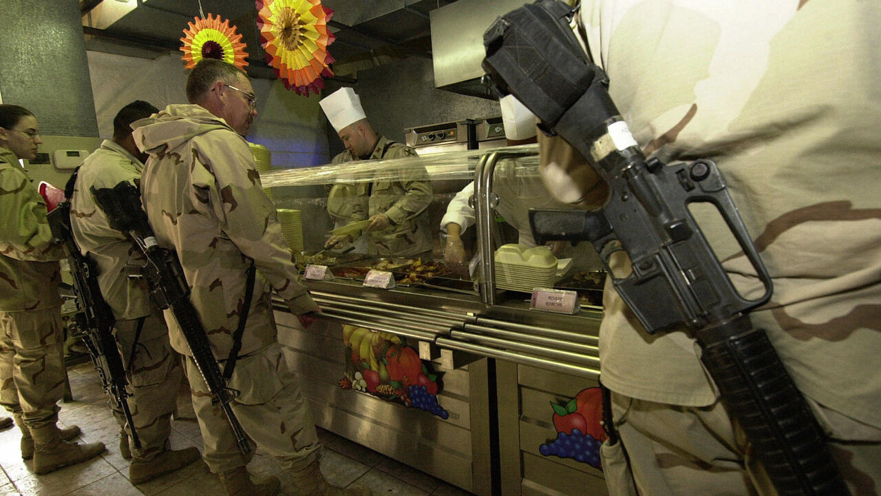 NIC2004122211267 MOSUL, IRAQ: (FILES)-A US officer from the 1st Brigade, 25th Infantry Division (Stryker Brigade Combat Team) serves turkey for soldiers lining up for a traditional Thanksgiving meal at a dinning room in a US base in the northern Iraqi city of Mosul, 25 November 2004. A huge explosion at this US army mess hall killed 22 people in the deadliest single attack against US forces in Iraq yesterday 21 December 2004. AFP PHOTO/TAUSEEF MUSTAFA (Photo credit should read TAUSEEF MUSTAFA/AFP/Getty Images)