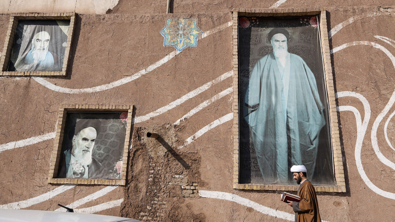 1094178486 A Muslim Shiite cleric walks past the house of the late founder of the Islamic Republic, Ayatollah Ruhollah Khomeini, in the holy city of Qom, 130 kilometres south of Tehran on January 15, 2019. - In the religious capital of Iran, the Islamic revolution still holds a powerful sway even as once-unthinkable signs of modernity creep into the city of Qom to challenge the faithful. Qom, a couple of hours drive south of Tehran, is one of Shiite Islam's holiest sites, home to dozens of seminaries and many of its m