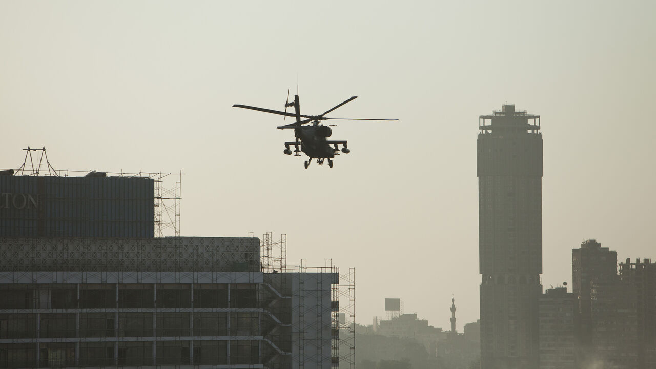 75665343 CAIRO, EGYPT - JULY 26: An Egyptian Army Apache helicopter flies over the Cairo skyline during pro-military demonstrators at Tahrir Square on July 26, 2013 in Cairo, Egypt. Protesters gathered to show support to the overthrow of Egyptian President Mohammed Morsi by the Egyptian military on July 3, after a speech made Wednesday by the Chief of Egypt's Armed Forces, General Ahmed Fattah al-Sissi, who called for mass anti-Morsi protests across Egypt on Friday against 'violence and terrorism'. Egyptian authori