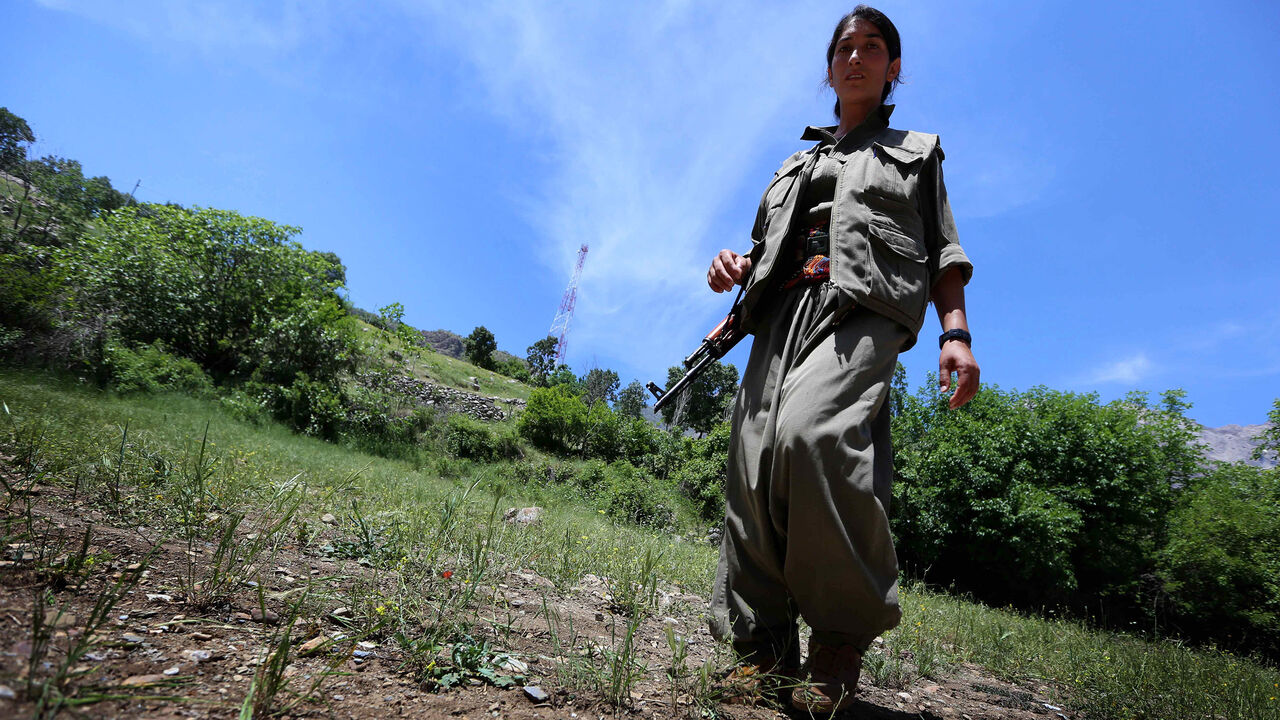 Nic6324230 A female member of the anti-Iranian group, the Party of Free Life of Kurdistan (PJAK), carries her weapon as she walks through their base deep in the Qandil mountains of northern Iraq's Kurdish autonomous region, on May 5, 2014. AFP PHOTO/SAFIN HAMED (Photo credit should read SAFIN HAMED/AFP/Getty Images)