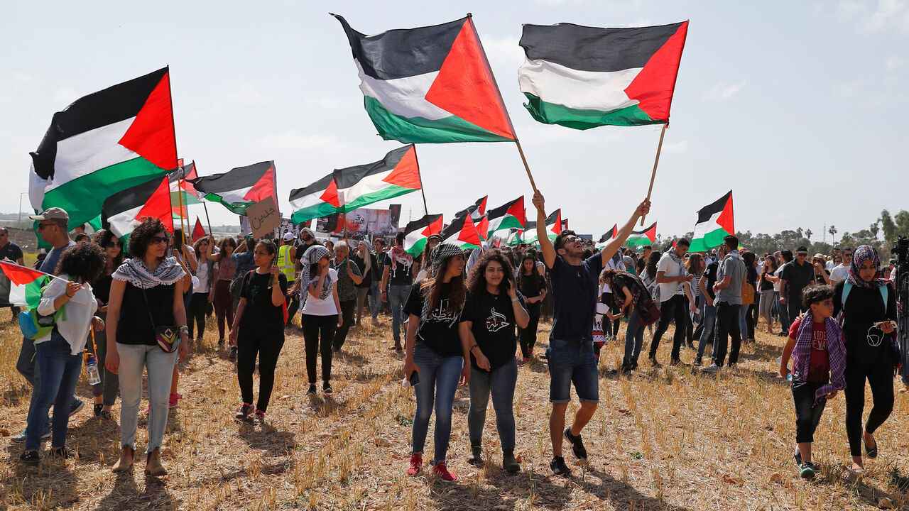 AFP_1458H9 Palestinian and Arab Israeli protesters wave Palestinian flags as they march for the right of return for Palestinian refugees who fled their homes or were expelled during the 1948 war that followed the creation of the state of Israel, during the 70th anniversary of the Jewish state's founding, near Haifa in northern Israel, on April 19, 2018. (Photo by AHMAD GHARABLI / AFP) (Photo credit should read AHMAD GHARABLI/AFP/Getty Images)