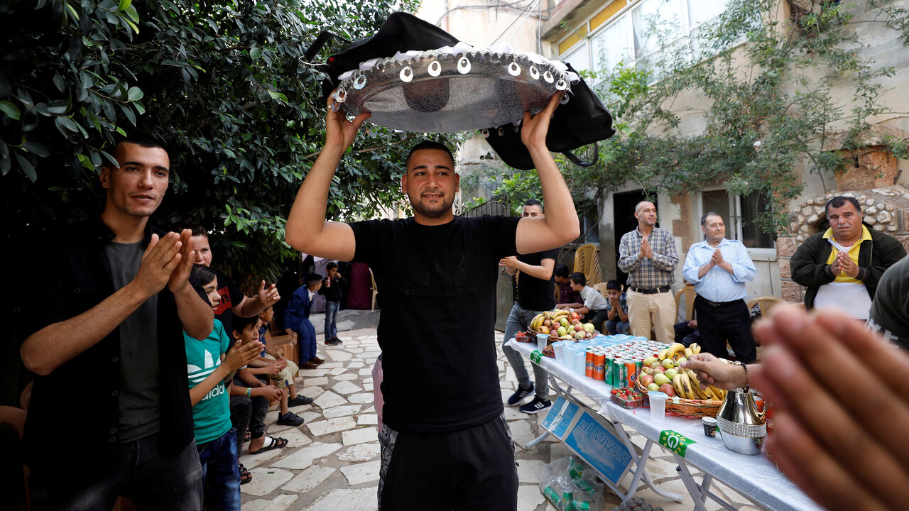 GLOBAL-WEDDINGS/ Palestinian groom Hejres Torokman carries his suit over his head as he prepares for his wedding party, in Jenin in the occupied West Bank May 7, 2018. Picture taken May 7, 2018. REUTERS/Mohamad Torokman - RC1A989FF9A0