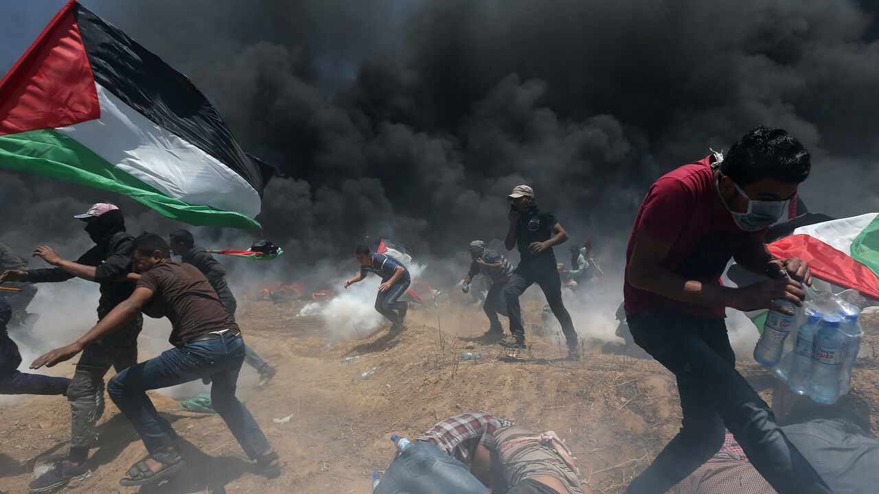 ISRAEL-USA/PROTESTS-PALESTINIANS Palestinian demonstrators run for cover from Israeli fire and tear gas during a protest against U.S. embassy move to Jerusalem and ahead of the 70th anniversary of Nakba, at the Israel-Gaza border in the southern Gaza Strip May 14, 2018. REUTERS/Ibraheem Abu Mustafa - RC1712A20510