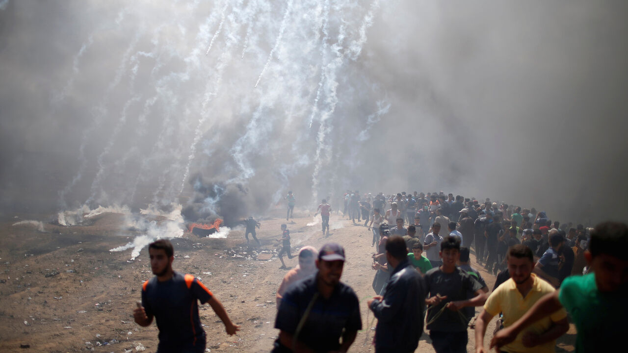 Palestinian demonstrators run from tear gas fired by Israeli troops during a protest against U.S. embassy move to Jerusalem and ahead of the 70th anniversary of Nakba, at the Israel-Gaza border east of Gaza City May 14, 2018. REUTERS/Mohammed Salem     TPX IMAGES OF THE DAY - RC1385445700