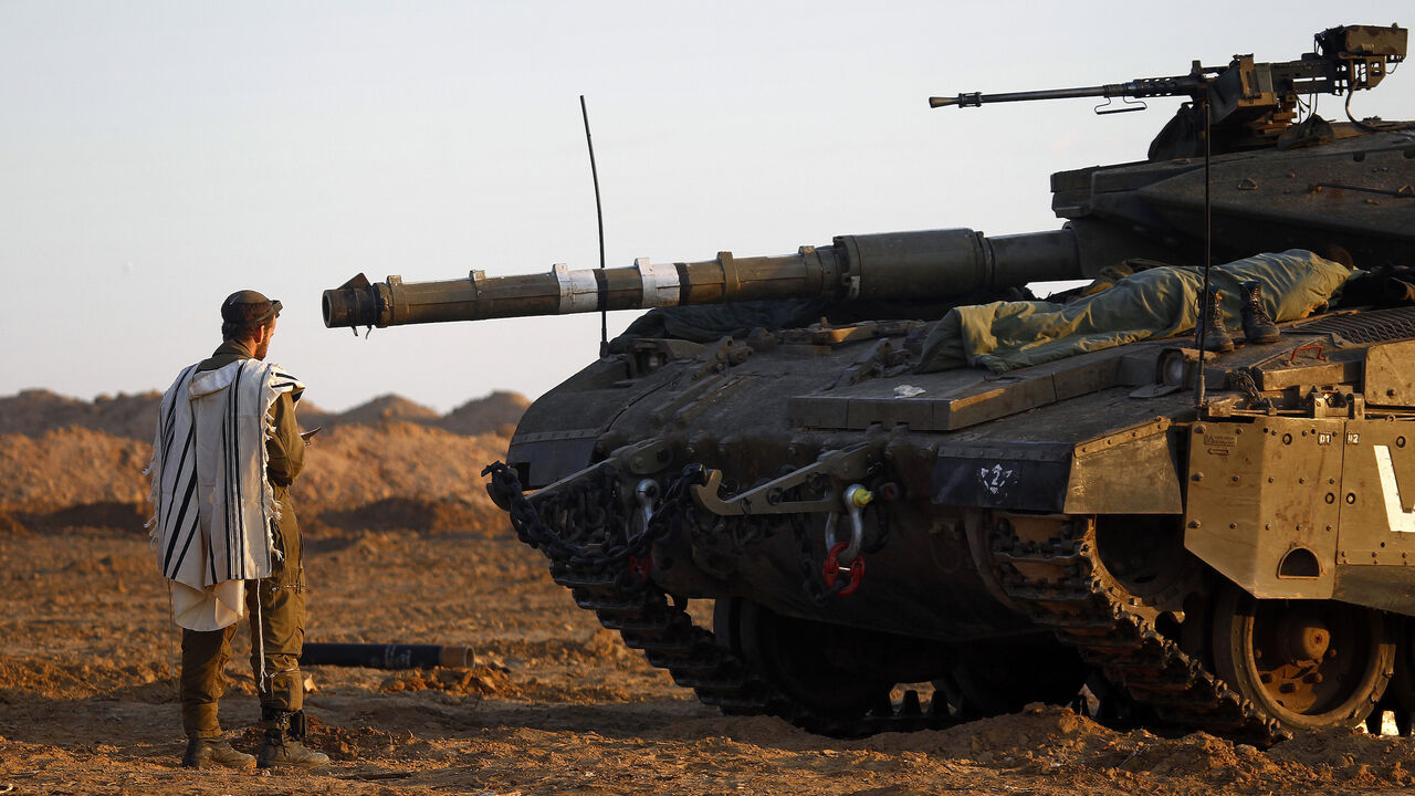 PALESTINIANS-ISRAEL/ An Israeli soldier prays by a tank at an Israeli Defence Forces (IDF) staging area in the central Gaza border November 21, 2012. Israeli air strikes shook the Gaza Strip and Palestinian rockets struck across the border as U.S. Secretary of State Hillary Clinton held talks in Jerusalem in the early hours of Wednesday, seeking a truce that can hold back Israel's ground troops. REUTERS/Yannis Behrakis (ISRAEL - Tags: CONFLICT CIVIL UNREST MILITARY RELIGION) - GM1E8BL143K01