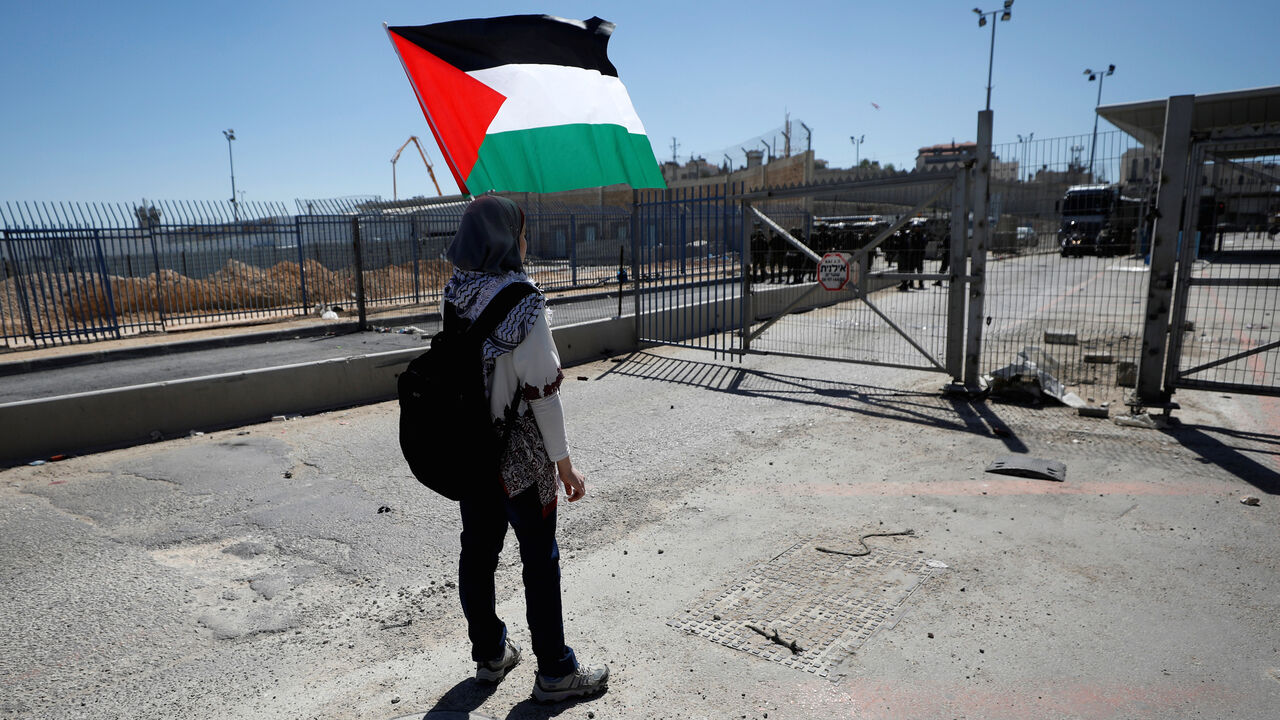 WOMENS-DAY/ISRAEL-PALESTINIANS A girl holds a Palestinian flag in front of Israeli troops during clashes at a protest against U.S. President Donald Trump's decision on Jerusalem ahead of International Women's Day, in Ramallah, in the occupied West Bank March 7, 2018. REUTERS/Mohamad Torokman - RC1596807590
