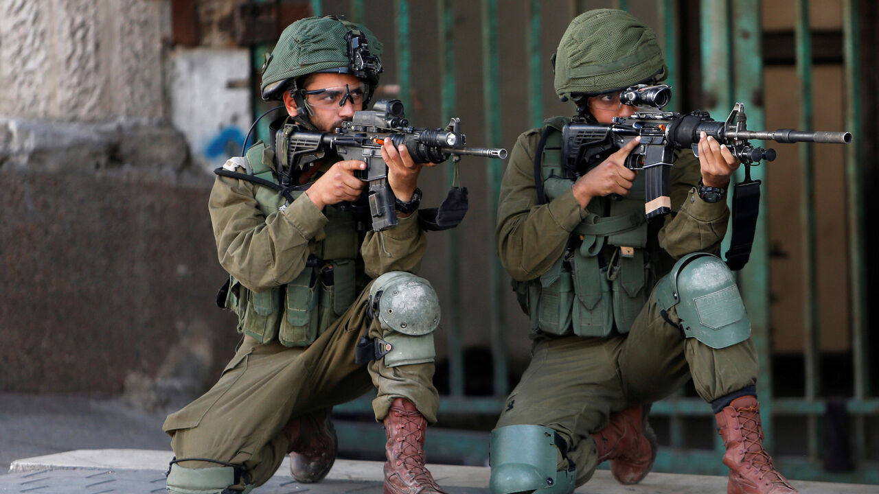 ISRAEL-PALESTINIANS/PROTESTS Israeli soldiers aim their weapons during a protest by Palestinians ahead of the 70th anniversary of Nakba, in Hebron in the occupied West Bank May 11, 2018. REUTERS/Mussa Qawasma - RC1AAAFDAA20