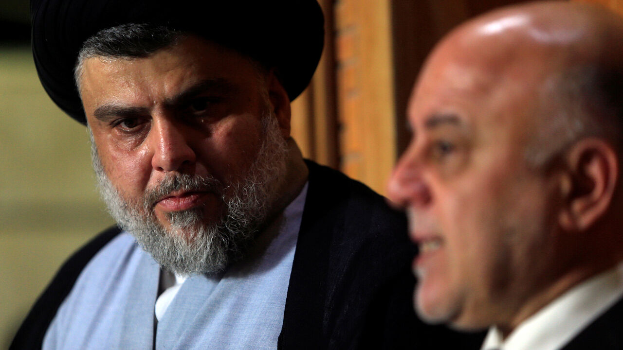 IRAQ-ELECTION/ Iraqi Shi'ite cleric Moqtada al-Sadr, who's bloc came first, looks at Iraqi Prime Minister Haider al-Abadi, who's political bloc came third in a May parliamentary election, during a news conference in Najaf, Iraq June 23, 2018. REUTERS/Alaa al-Marjani - RC1D0E2C2810