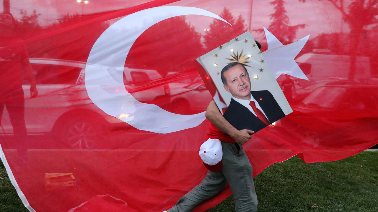 TURKEY-ELECTION/ A supporters of Turkish President Tayyip Erdogan holds his picture in front of a Turkish flag, in front of Turkey's ruling AK Party (AKP) headquarters in Istanbul,Turkey, June 24, 2018. REUTERS/Goran Tomasevic TPX IMAGES OF THE DAY - RC1D72DCC500
