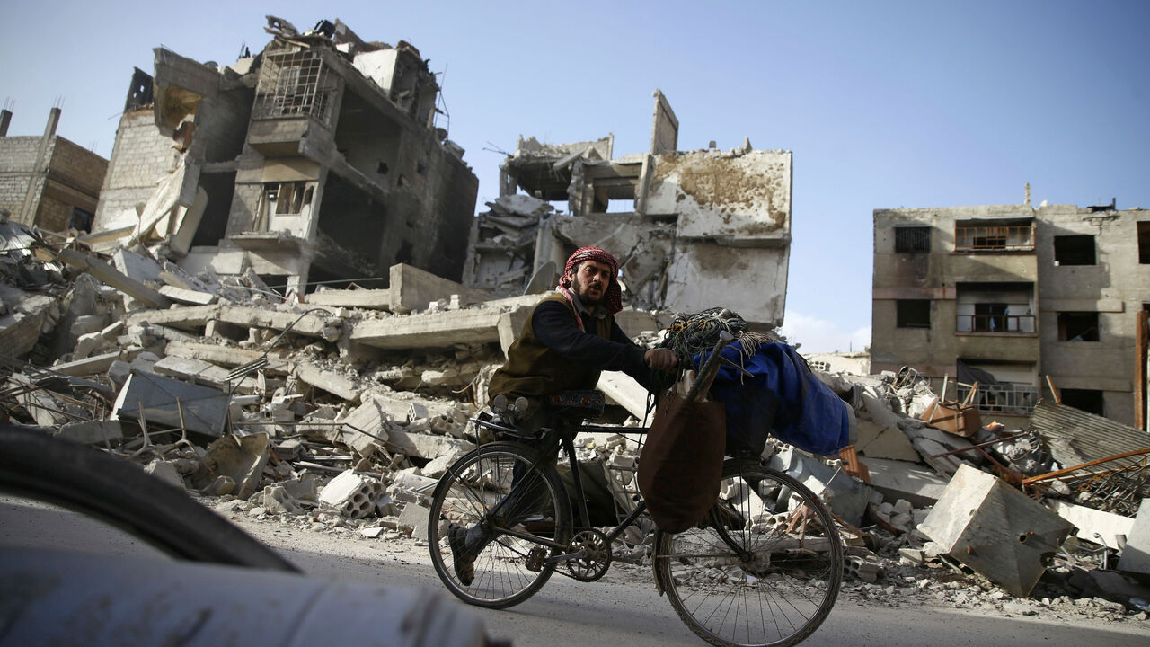 MIDEAST-CRISIS/SYRIA-GHOUTA A handicapped man rides a bicycle past damaged buildings in the besieged town of Douma in eastern Ghouta in Damascus, Syria, March 1, 2018. REUTERS/Bassam Khabieh - RC19231603F0
