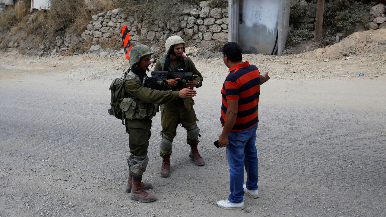 ISRAEL-PALESTINIANS/ A Palestinian man stands in front of Israeli soldiers near the scene of attempted car ramming attack, in Hebron in the occupied West Bank June 2, 2018. REUTERS/Mussa Qawasma - RC1F06CFB530