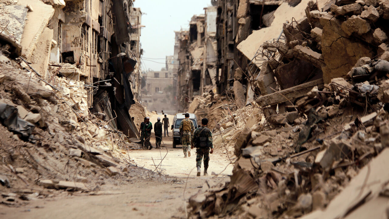 MIDEAST-CRISIS/SYRIA Soldiers walk past damaged buildings in Yarmouk Palestinian camp in Damascus, Syria May 22, 2018. REUTERS/Omar Sanadiki - RC18889192B0