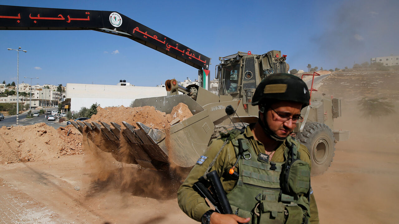 ISRAEL-PALESTINIANS/ An Israeli soldier stands guard as an Israeli military bulldozer opens the entrance of the West Bank village of Bani Na'im, near Hebron September 21, 2016. REUTERS/Ammar Awad - S1BEUCPBUNAA