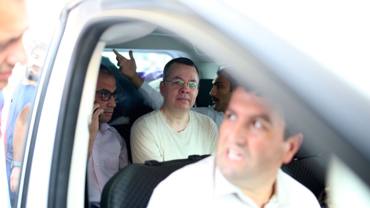 AFP_17X4EX US Pastor Andrew Craig Brunson (C), is seen inside a car escorted by Turkish plain clothes police officers as he arrives at his house on July 25, 2018 in Izmir. - A Turkish court on July 25, 2018 ruled to place under house arrest US pastor who has been imprisoned for almost two years on terror-related charges in a case that has raised tensions with the United States, state media said. The state-run Anadolu news agency said he was being put under house arrest, although it was not clear if he had already lef
