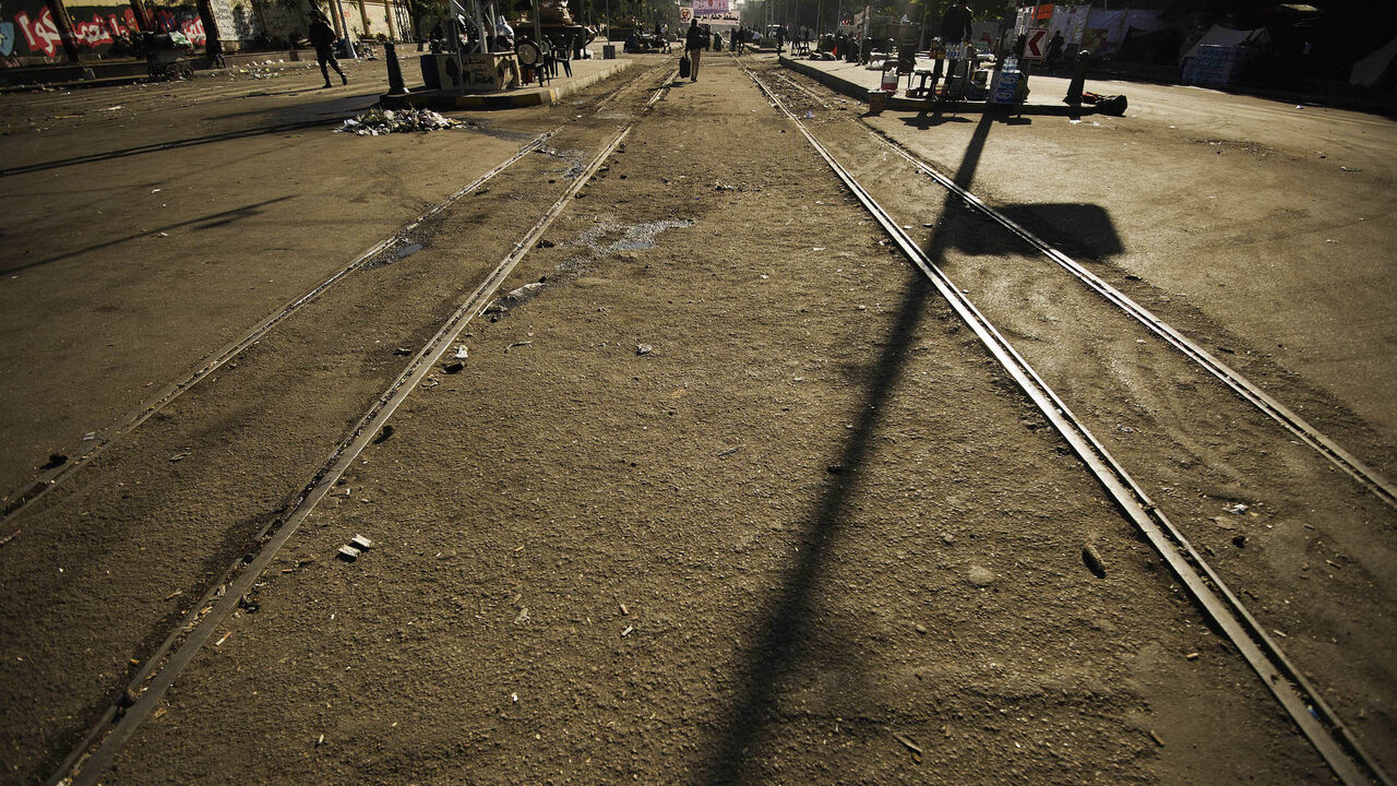 People walk on a railway track as Egyptian army troops are deployed outside the of the presidential palace in Cairo on December 12, 2012, one day after thousands of Egyptians protested against the upcoming referendum on the new draft constitution. Egypt's powerful army has called for President Mohamed Morsi and the secular opposition to meet later in the day to stop a crisis over an imminent constitutional referendum from tearing the country apart. AFP PHOTO/GIANLUIGI GUERCIA        (Photo credit should rea