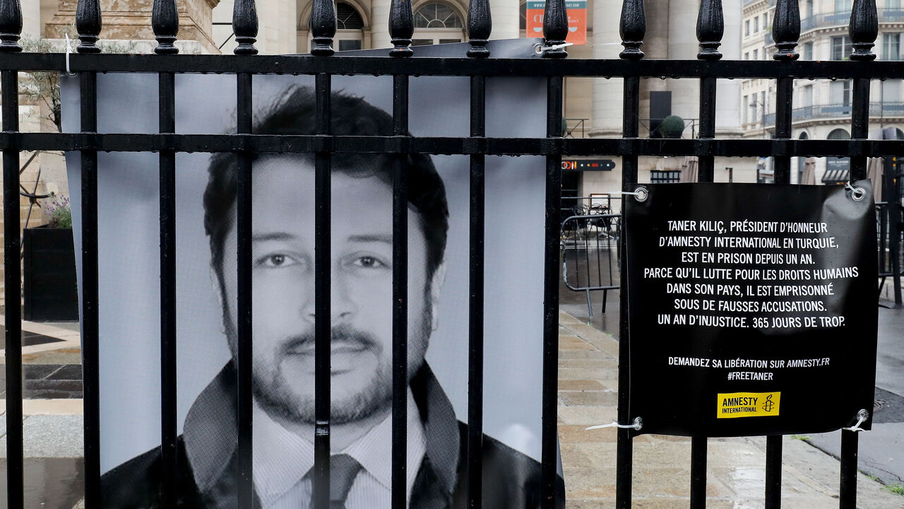 AFP_15N6L1 A portrait of rights group NGO Amnesty International's chairman in Turkey Taner Kilic is hung on June 6, 2018 on the fence of the historic French stock market building "Palais Brongniart" in Paris, to protest against Kilic's custody since a year for allegedly belonging to the movement led by an US-based Muslim preacher, whom Turkey accuses of ordering the 2016 coup bid. (Photo by FRANCOIS GUILLOT / AFP) (Photo credit should read FRANCOIS GUILLOT/AFP/Getty Images)