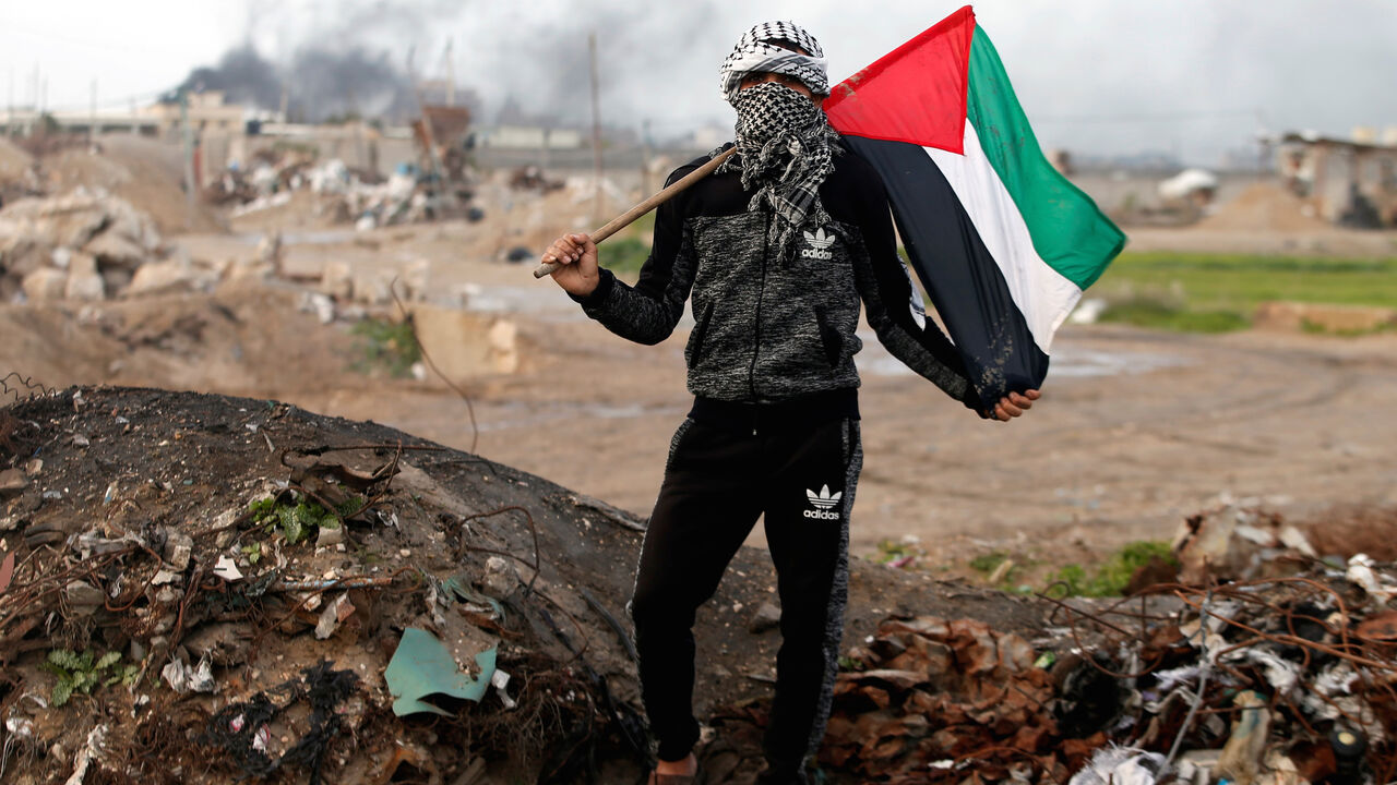 ISRAEL-PALESTINIANS/POLITICS A protester holds a Palestinian flag as he poses for a photograph at the scene of clashes with Israeli troops near the border with Israel, east of Gaza City, January 19, 2018. "The battle between us and the Israeli occupation has been ongoing for decades. We will continue to protest and resist as long as there is one Israeli occupier on our land. Trump and anyone else in this world will not be able to control our anger," he said. REUTERS/Mohammed Salem SEARCH "PROTESTER PALESTINIAN" FOR THIS STORY. S