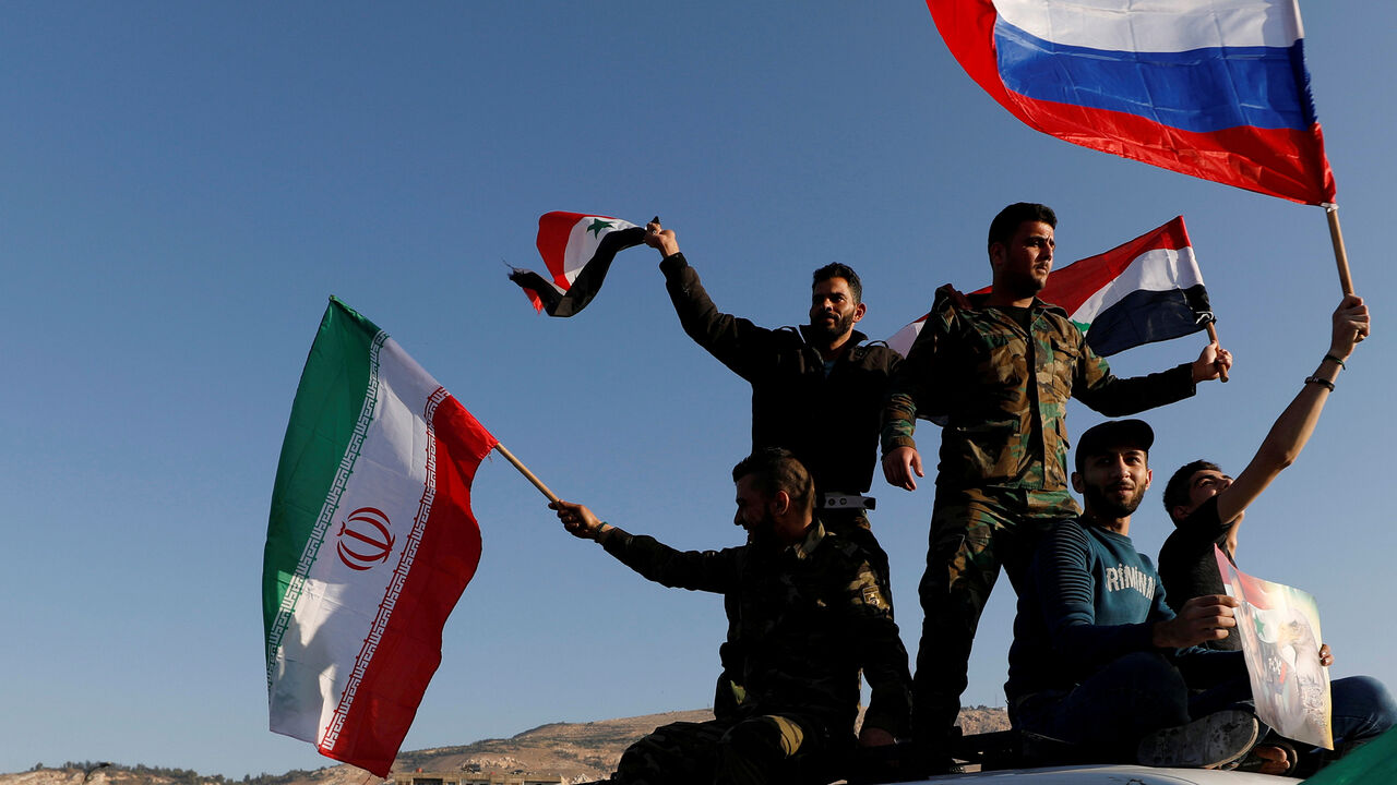 MIDEAST-CRISIS/SYRIA Syrians wave Iranian, Russian and Syrian flags during a protest against U.S.-led air strikes in Damascus,Syria April 14,2018.REUTERS/ Omar Sanadiki - RC151A9ED3D0