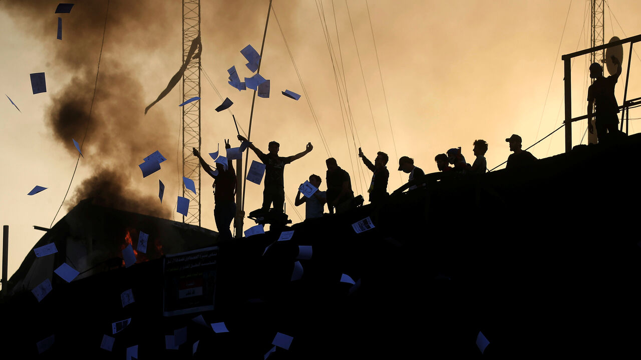 IRAQ-PROTESTS/ Protesters throw documents as they stand on concrete blast walls during an anti-government protest near the burnt building of the government office in Basra, Iraq September 7, 2018. REUTERS/Alaa al-Marjani - RC1B9ABCCF30