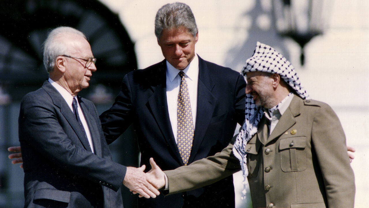ISRAEL-PALESTINIANS/OSLO/ PLO Chairman Yasser Arafat (R) shakes hands with Israeli Prime Minister Yitzhak Rabin (L), as U.S. President Bill Clinton stands between them, after the signing of the Israeli-PLO peace accord, at the White House in Washington September 13, 1993. REUTERS/Gary Hershorn (UNITED STATES - Tags: POLITICS) - GM1E99D1UCD01