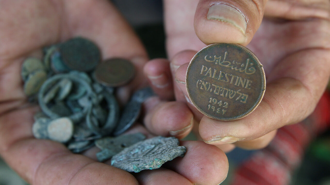 PALESTINIANS-ISRAEL/SALARIES A Palestinian man displays an old Palestinian coin in his shop in the West Bank city of Hebron June 8, 2008. The Palestinian Authority has delayed paying its workers this month after Israel withheld tax funds in anger over Palestinian attempts to block upgraded European Union-Israeli ties, officials said on Sunday. REUTERS/Nayef Hashlamoun (WEST BANK) - GM1E469047K01
