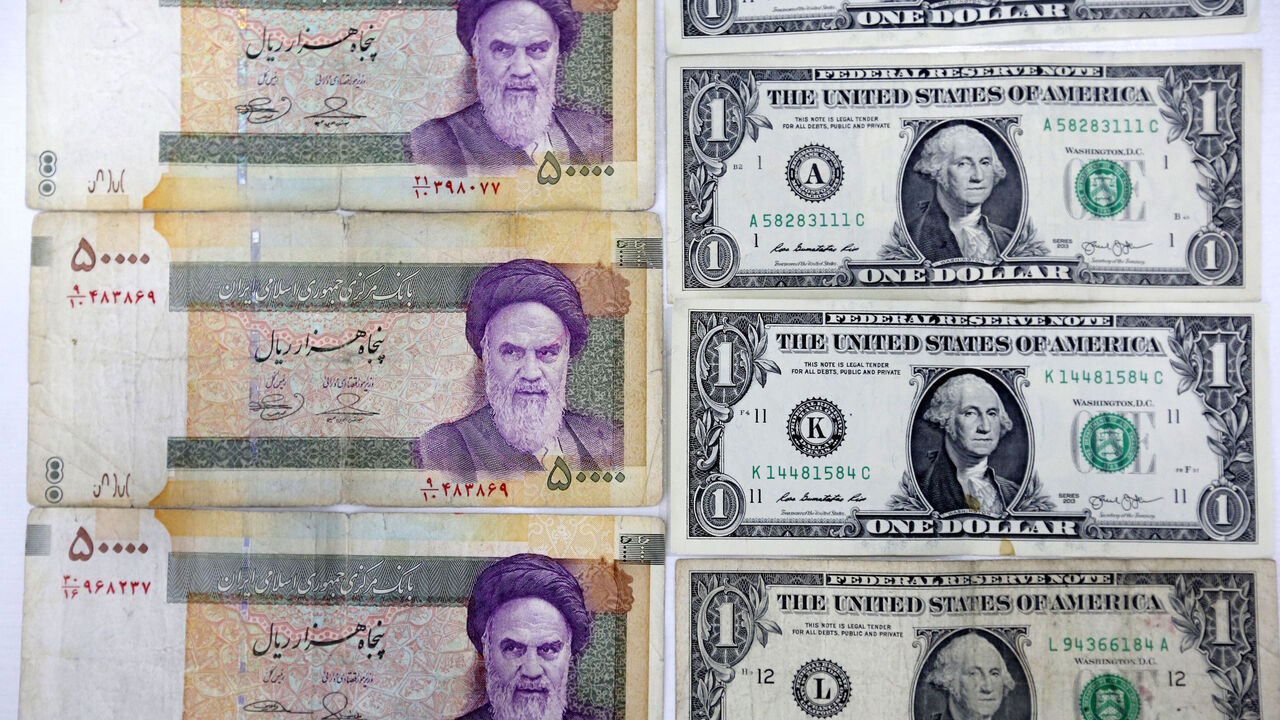 AFP_13V66V A close up shot shows Iran's various Rial banknotes, bearing a portrait of Iran's late founder of Islamic Republic Ayatollah Ruhollah Khomeini, next to United States one-Dollar bills bearing a portrait of first US President, George Washington in Tehran on April 10, 2018. - Iran took the drastic step of fixing the rate of its currency against the dollar in a bid to arrest a slide that has seen it fall by a third in six months. (Photo by ATTA KENARE / AFP) (Photo credit should read ATTA KENARE/AFP/Gett