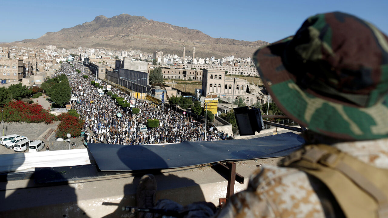 YEMEN-SECURITY/ A Houthi militant sits guard on the roof of a building overlooking fellow Houthis rallying to denounce the rapid devaluation of the Yemeni Rial in Sanaa, Yemen October 5, 2018. REUTERS/Khaled Abdullah - RC149994CBB0