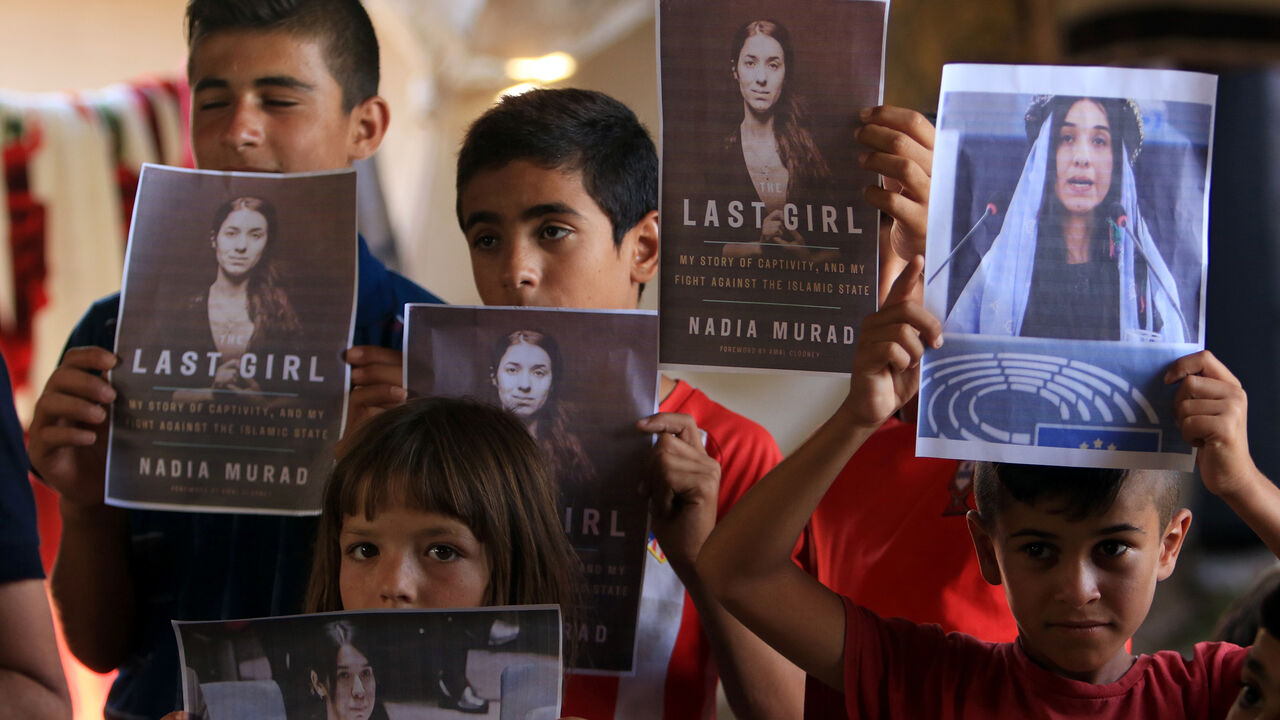 NOBEL-PRIZE/PEACE Yazidi children hold pictures of Nadia Murad, who won the Nobel Peace prize, in Duhok, Iraq October 5, 2018. REUTERS/Ari Jalal - RC1A9917F900