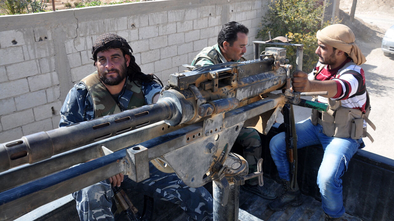 AFP_TQ7FD Syrian soldiers and pro-regime militiamen man a heavy machine-gun mounted on the back of a pickup truck as they ride in the recently retaken desert town of Al-Qaryatain on October 26, 2017.
The Syrian Observatory for Human Rights, a Britain-based monitor, reported on October 23, 2017 that Islamic State (IS) group militants massacred more than 100 people in the desert town of Al-Qaryatain during the month before they lost it to regime forces.
Before the civil war broke out in 2011, al-Qaryatain was a symbol