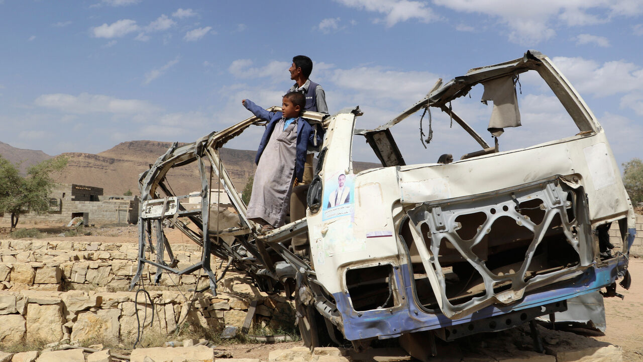 YEMEN-SECURITY/CHILDREN Abdullah al-Khawlani stands with his son, Hafidh, who survived a Saudi-led air strike stand on the wreckage of a bus destroyed by the strike in Saada, Yemen September 4, 2018. Another son of al-Khawlani was killed by the strike. Picture taken September 4, 2018. REUTERS/Naif Rahma - RC1F0E3F8DD0