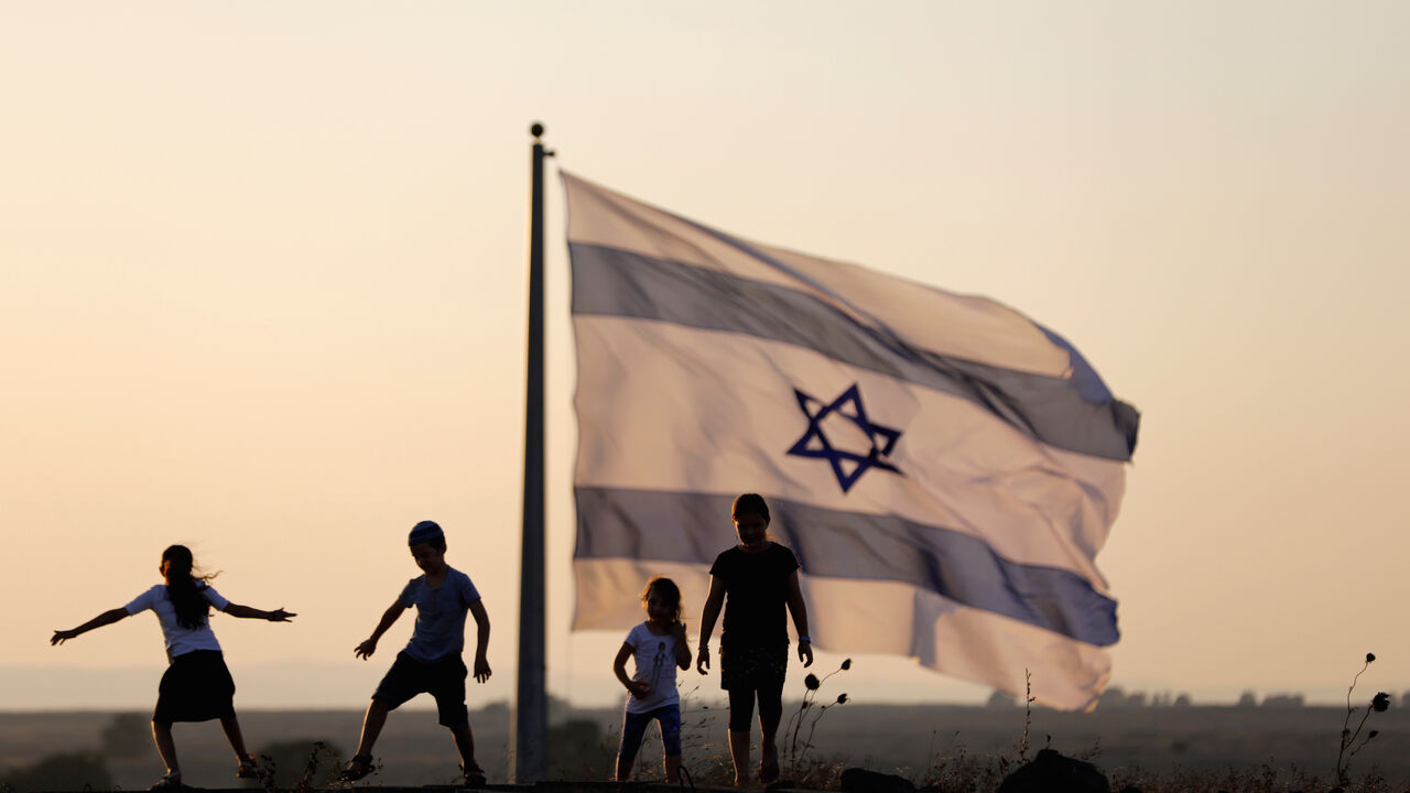 MIDEAST-CRISIS/SYRIA-ISRAEL Israeli kids play next to an Israeli flag next to the Israeli Syrian border at the Israeli-occupied Golan Heights, Israel July 23, 2018. REUTERS/Ronen Zvulun - RC179A5708F0