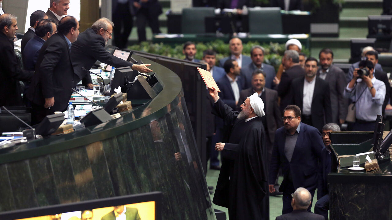 AFP_1BT6O0 Iranian President Hassan Rouhani (C-R) submits documents outlining his budget for 2018-2019 to Parliament Speaker Ali Larijani (4th-L) in the capital Tehran on December 25, 2018. (Photo by ATTA KENARE / AFP) (Photo credit should read ATTA KENARE/AFP/Getty Images)