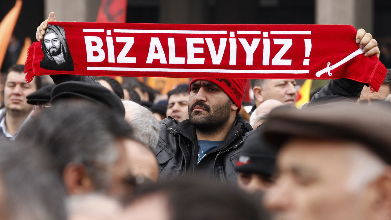 TURKEY-PROTEST/ A protester holds a banner reading "we are alevi" as he and many others wait to hear the decision of the court in front of a courthouse in Ankara March 13, 2012. Turkish police fired tear-gas and water cannon to disperse hundreds protesting on Tuesday against the dropping of a case against five people charged with killing 37 writers and liberals in a 1993 hotel fire set off by Islamist rioters.The opposition accused Prime Minister Tayyip Erdogan and his AK Party, which emerged from a series of banned Islami