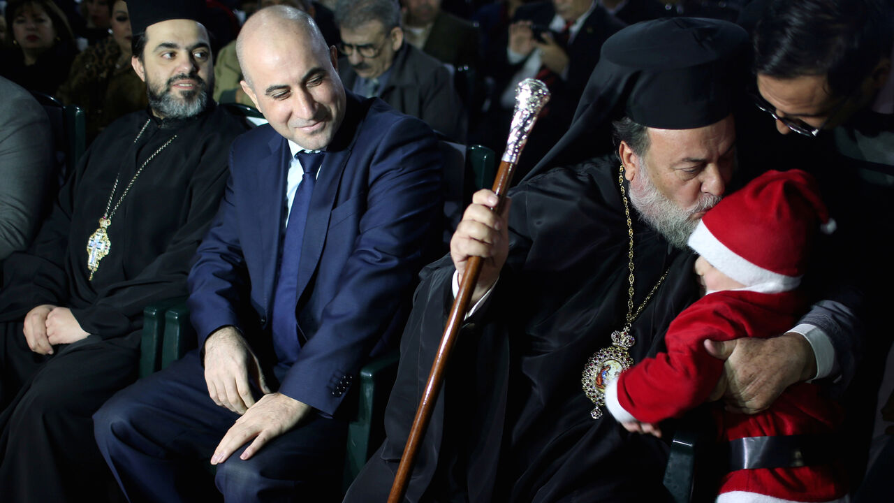 CHRISTMAS-SEASON/GAZA Greek Orthodox Archbishop Alexios kisses a Palestinian child dressed up as Santa Claus during a Christmas tree lighting ceremony in Gaza City December 22, 2018. Picture taken December 22, 2018. REUTERS/Ibraheem Abu Mustafa - RC15B4F1FD50