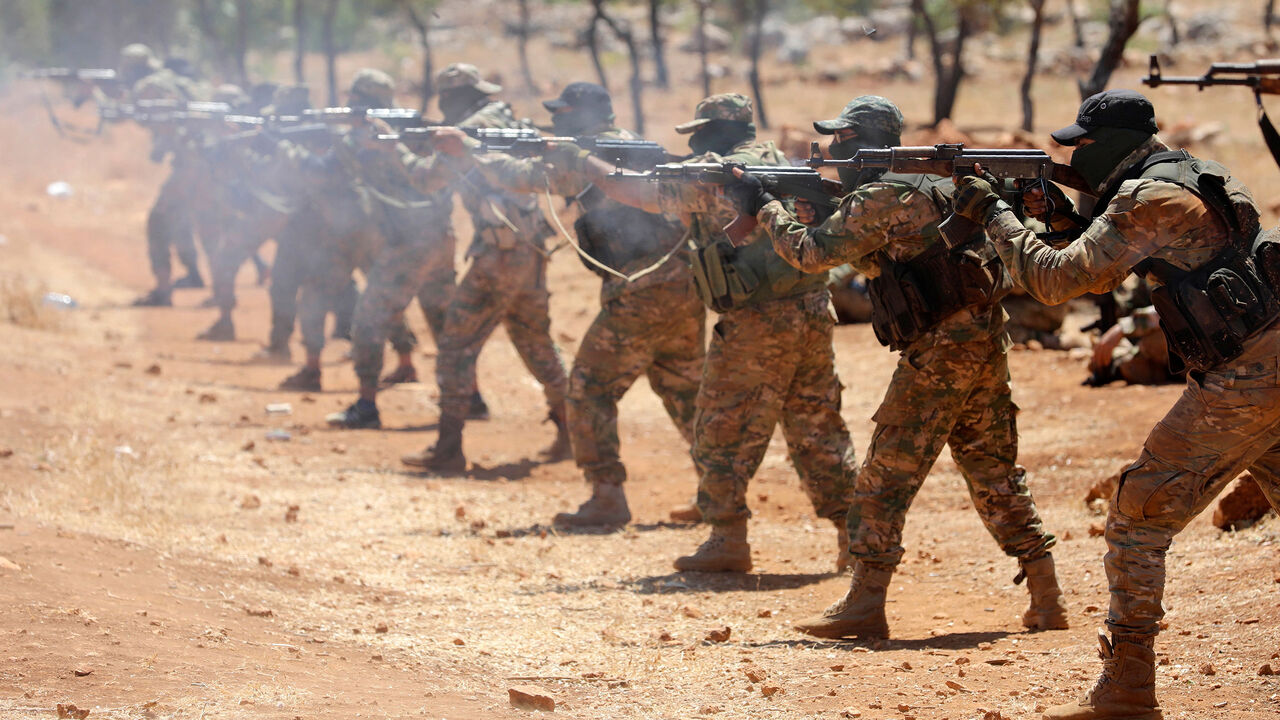 AFP_18D4JL Syrian fighters fire AK-47 rifles as they attend a mock battle in anticipation of an attack by the regime on Idlib province and the surrounding countryside, during a graduation of new Hayat Tahrir al-Sham (HTS) members at a camp in the countryside of the northern Idlib province on August 14, 2018. (Photo by OMAR HAJ KADOUR / AFP) (Photo credit should read OMAR HAJ KADOUR/AFP/Getty Images)