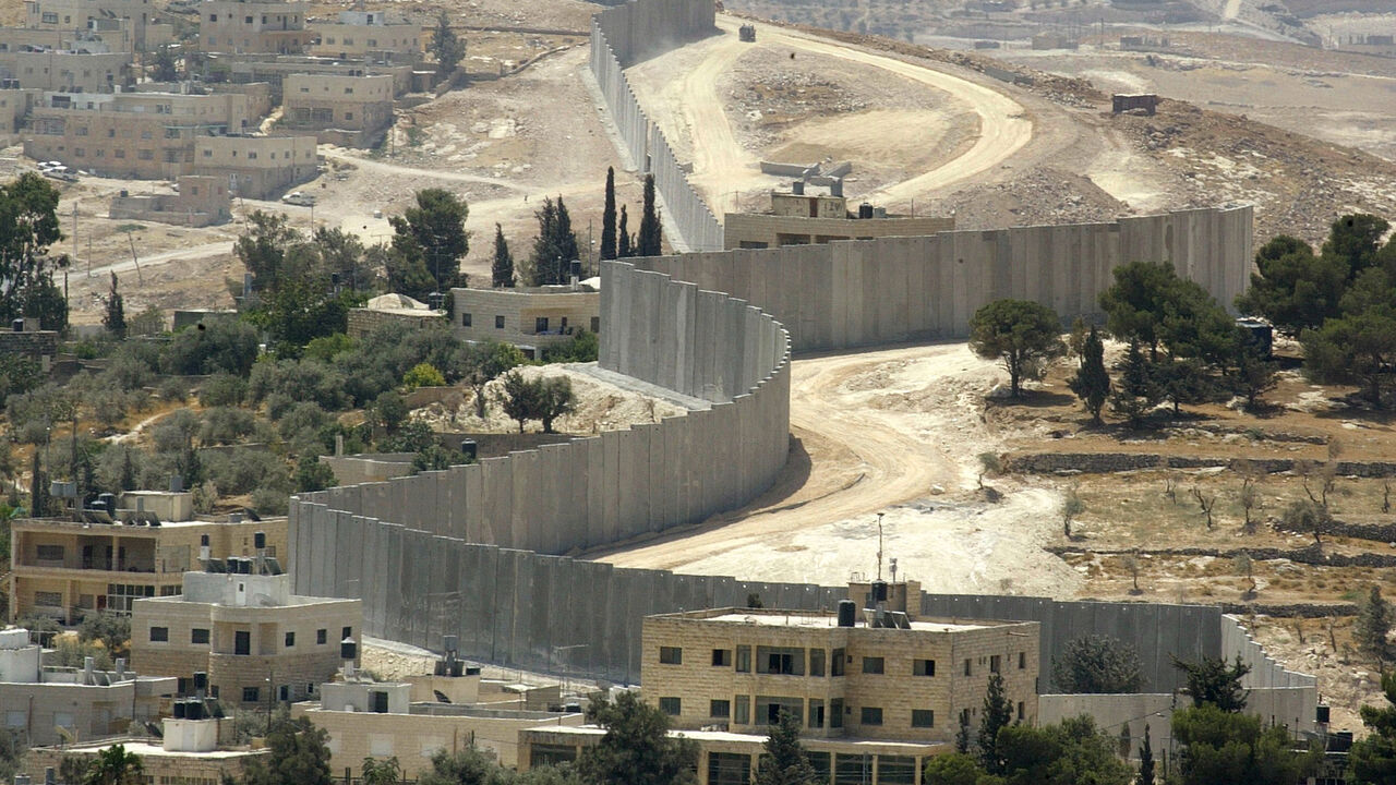 MIDEAST A general view shows the concrete wall, part of Israel's controversial security barrier, which seperates the eastern neighbourhoods of Jerusalem from the West Bank town of Abu Dis (L) July 16, 2004.The U.N. General Assembly is drawing up a draft resolution demanding that Israel obey a World Court ruling and tear down its West Bank wall as Israeli Tourism Minister Gideon Ezra was quoted as saying that it should be turned into a must-see tourist attraction to help visitors understand the country's security pr