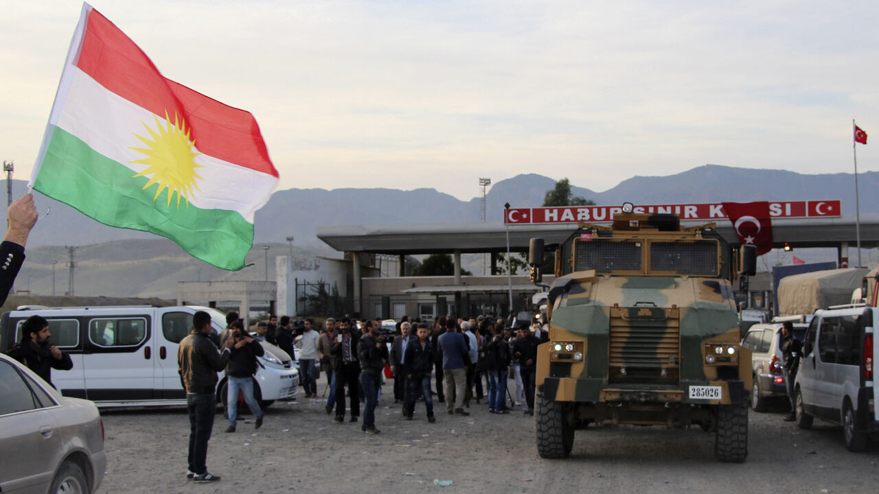MIDEAST-CRISIS/PESHMERGA A man waves a Kurdistan flag as a Turkish military truck escorts a convoy of peshmerga vehicles at Habur border gate, which separates Turkey from Iraq, near the town of Silopi in southeastern Turkey, October 29, 2014. Iraqi peshmerga fighters arrived in southeastern Turkey early on Wednesday ahead of their planned deployment to the Syrian town of Kobani to help fellow Kurds repel an Islamic State advance, a Reuters witness said. REUTERS/Kadir Baris (TURKEY - Tags: POLITICS MILITARY CONFLICT TPX IMAGES OF TH