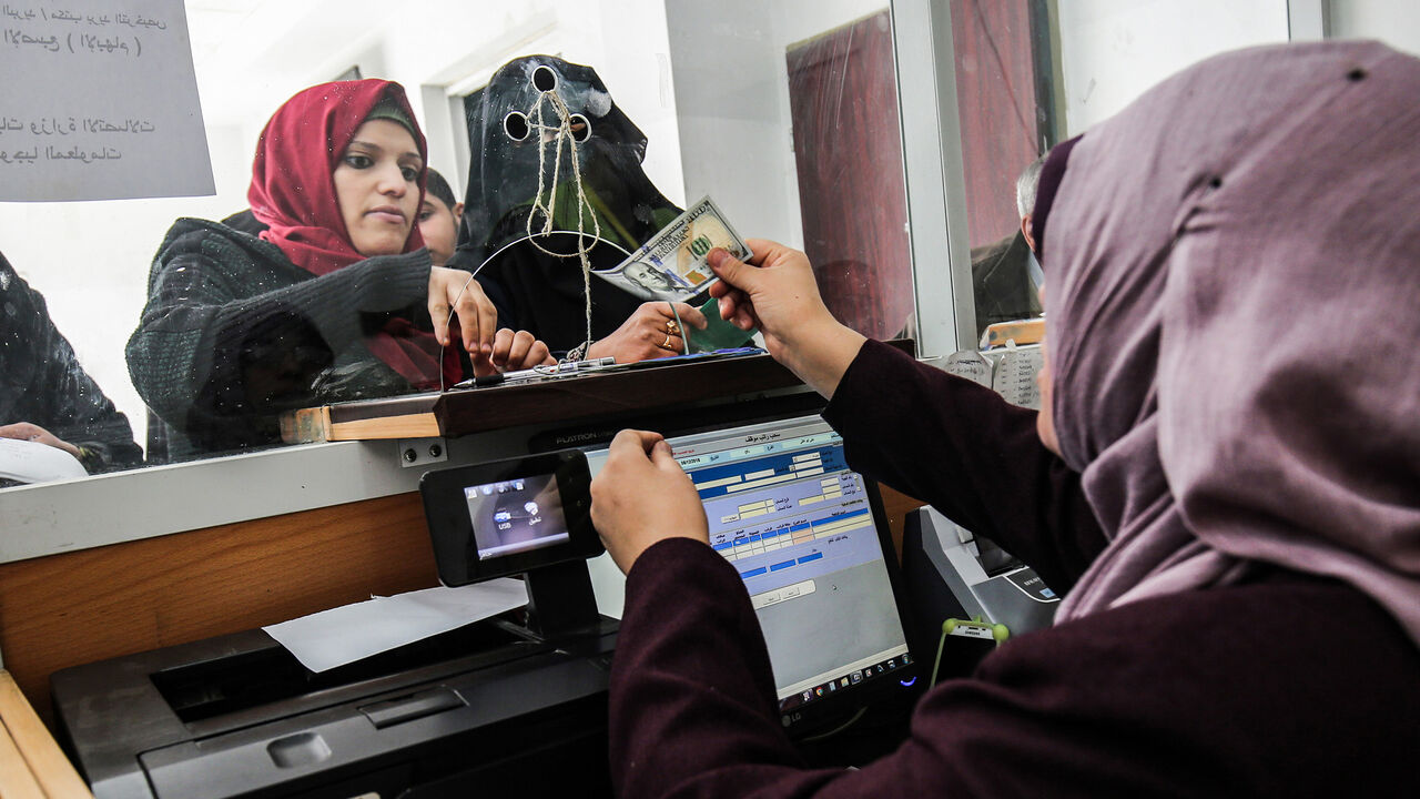 AFP_1BF6UH A Palestinian government employee receives a portion her his overdue salary at a post office in Rafah in the southern Gaza Strip on December 8, 2018, after the Hamas-run finance ministry had announced that the money would be distributed over the two days, with employees receiving 50 percent of their salaries. - Employees of the Hamas administration in the Gaza Strip began collecting their salaries for a second month on December 7, after Qatar pumped more money into the territory with Israel's blessings. The