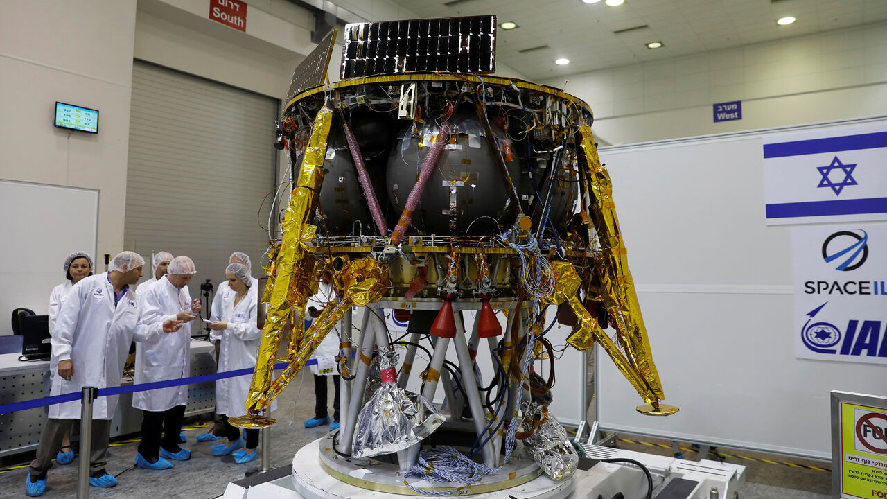 Israeli scientists stand next to an unmanned spacecraft which an Israeli team plans to launch into space at the end of the year and to land it on the Moon next year, in Yahud, Israel, July 10, 2018 REUTERS/Ronen Zvulun - RC1D8A2ADEC0