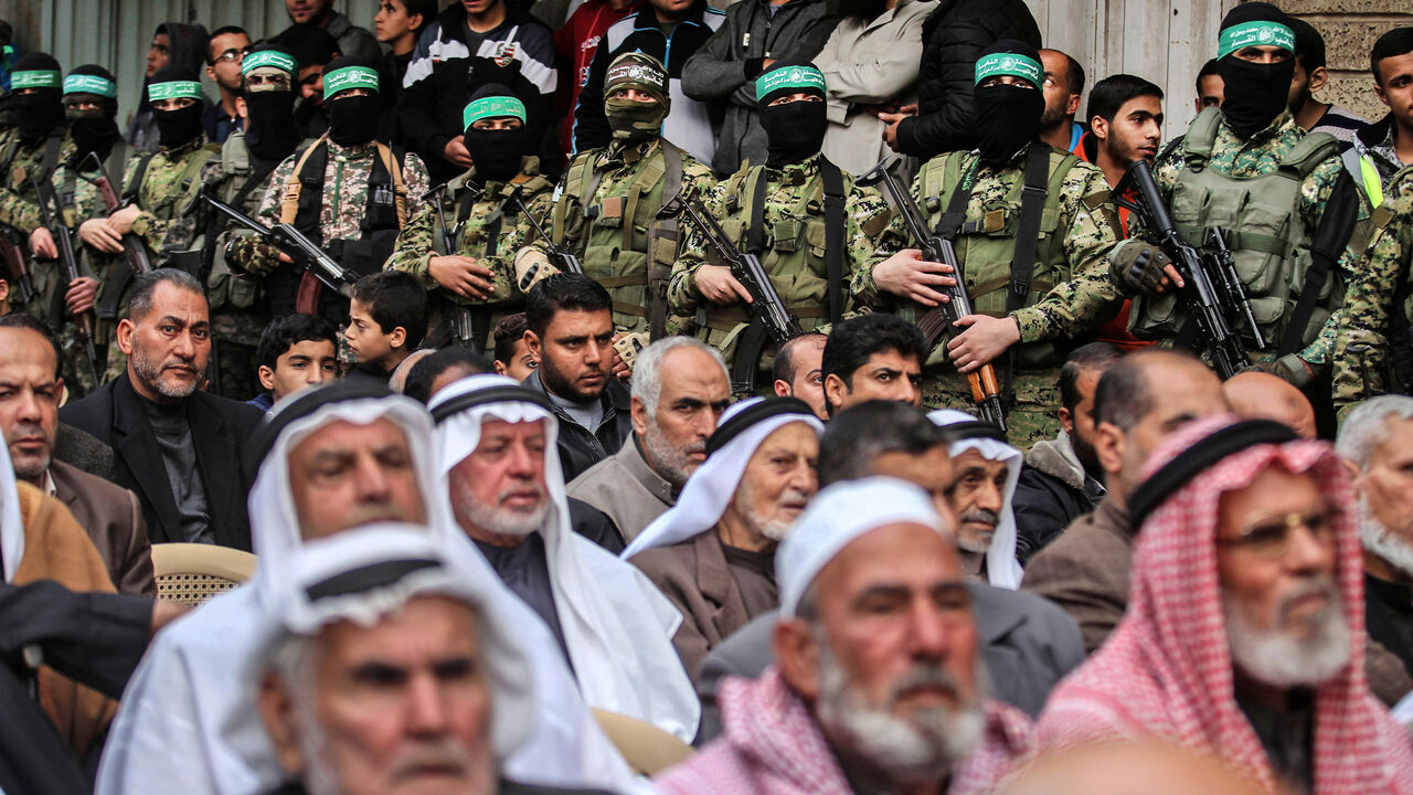 AFP_UW1UJ Palestinian men watch as fighters from the Ezzedine al-Qassam Brigades, the armed wing of the Palestinian Hamas movement, take part in a military show ahead of the 30th anniversary of the movement's founding in the southern Gaza Strip city of Khan Yunis on December 5, 2017. / AFP PHOTO / SAID KHATIB (Photo credit should read SAID KHATIB/AFP/Getty Images)