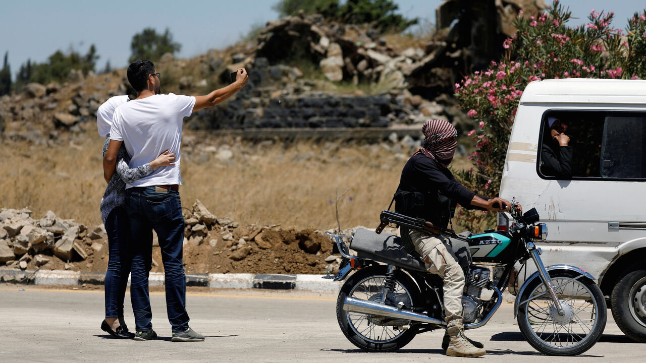 MIDEAST-CRISIS/SYRIA-QUNEITRA A rebel fighter rides on a motorbike as people take a selfie on a road in Quneitra, Syria July 27, 2018. REUTERS/Omar Sanadiki - RC1305C71BB0