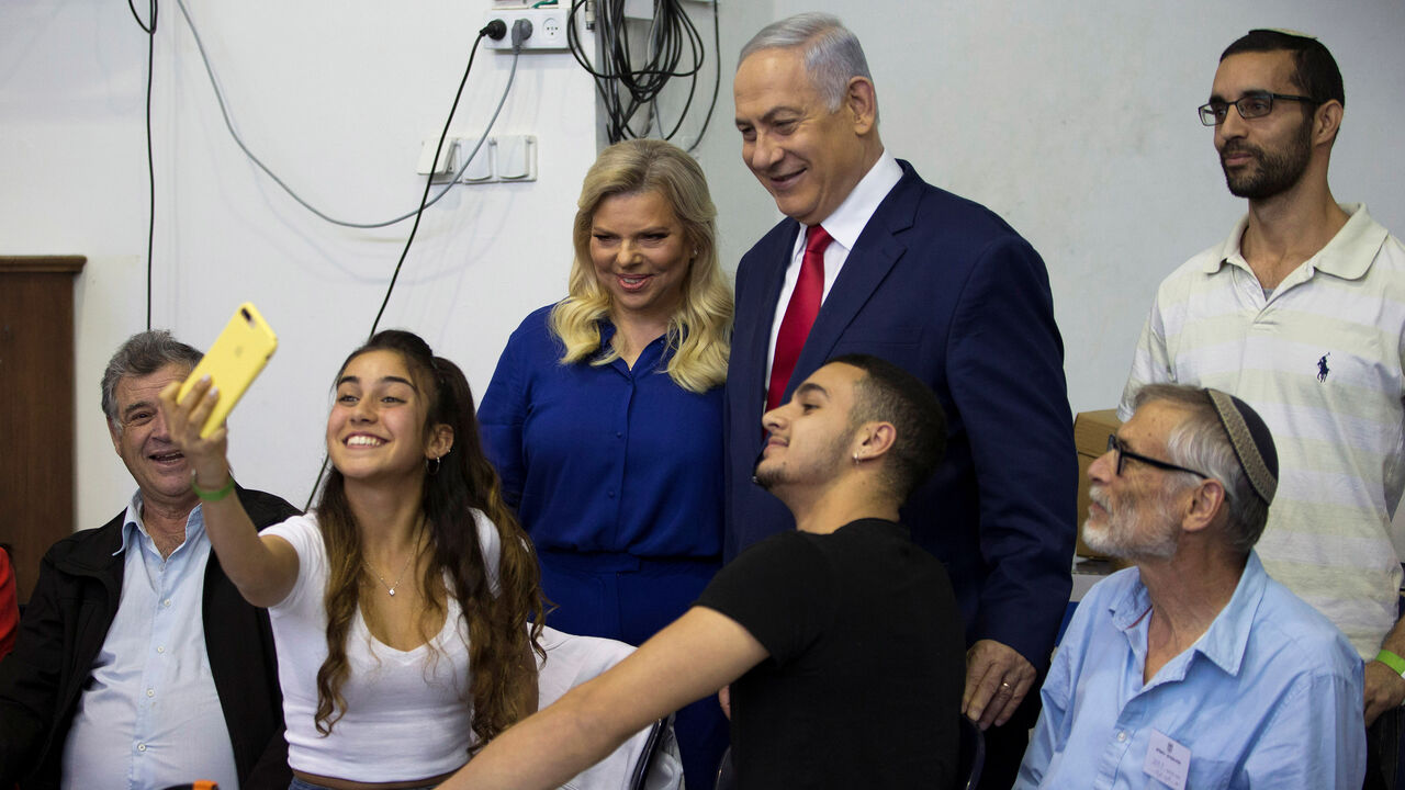 A youth takes a selfie with Israel's Prime Minister Benjamin Netanyahu and his wife Sara after they voted in Israel's parliamentary election in Jerusalem April 9, 2019. Ariel Schalit/Pool via REUTERS  *** Local Caption *** - RC18AF446110
