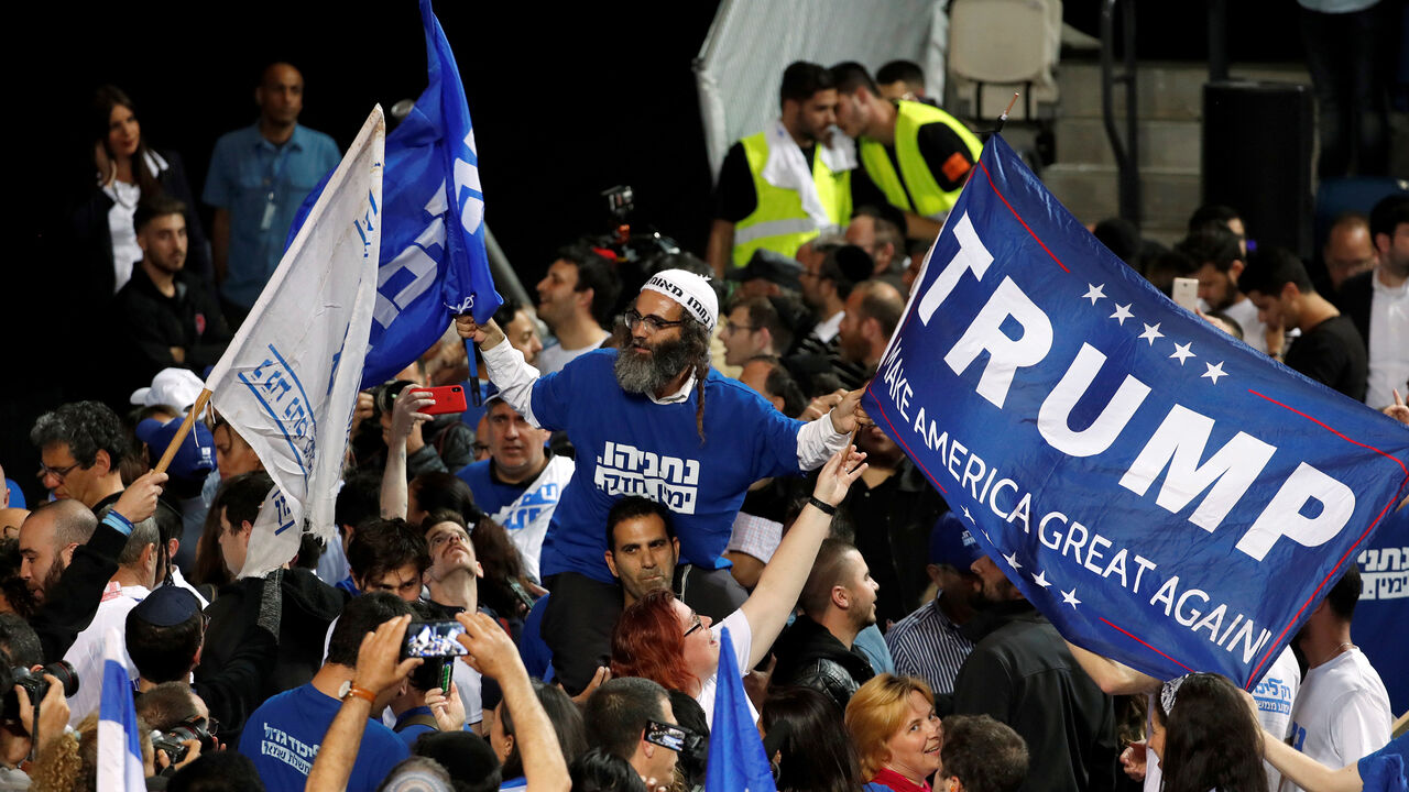 ISRAEL-ELECTION/ A supporter of Israeli Prime Minister Benjamin Netanyahu's Likud party waves flags, one bearing the name of U.S. President Donald Trump, as the crowd reacts to exit polls in Israel's parliamentary election at the party headquarters in Tel Aviv, Israel April 10, 2019. REUTERS/Ronen Zvulun - RC12929E4A50