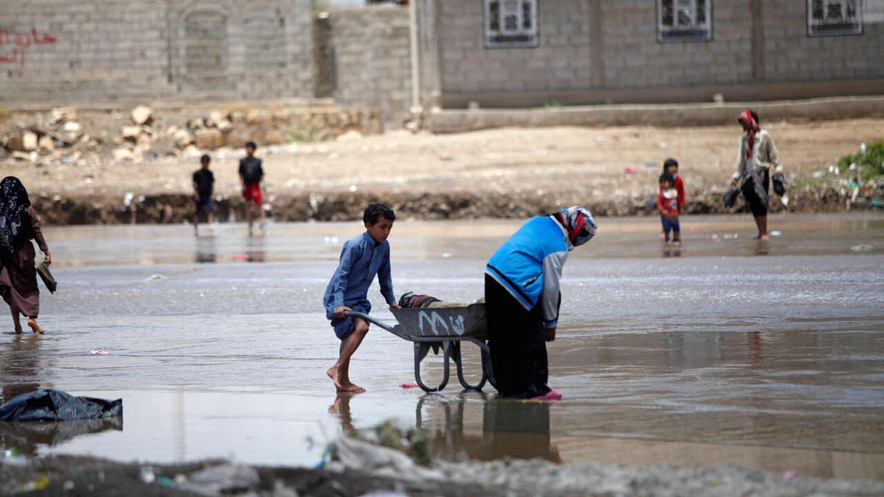 People carry their belongings washed by rain water after the heavy rain in Sanaa, Yemen April 17, 2020. REUTERS/Mohamed al-Sayaghi - RC2B6G94NE9H