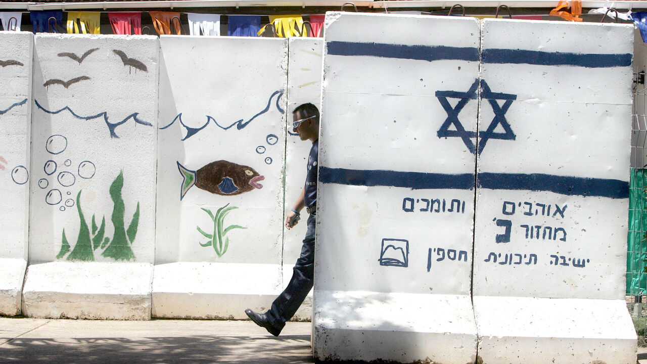 MIDEAST An Israeli settler walks between concrete walls for protection at the Jewish West Bank settlement of Ganim. An Israeli settler walks between concrete walls for protection at the Jewish West Bank settlement of Ganim, May 24, 2005. Ganim and another three Jewish settlements, Kadim, Homesh and Sa-Nur, at the northern part of the West Bank are about to be removed as part of Israel's disengagement plan in Gaza and north Samaria. Photo taken May 24, 2005. REUTERS/Nir Elias - RP6DRNASSZAC