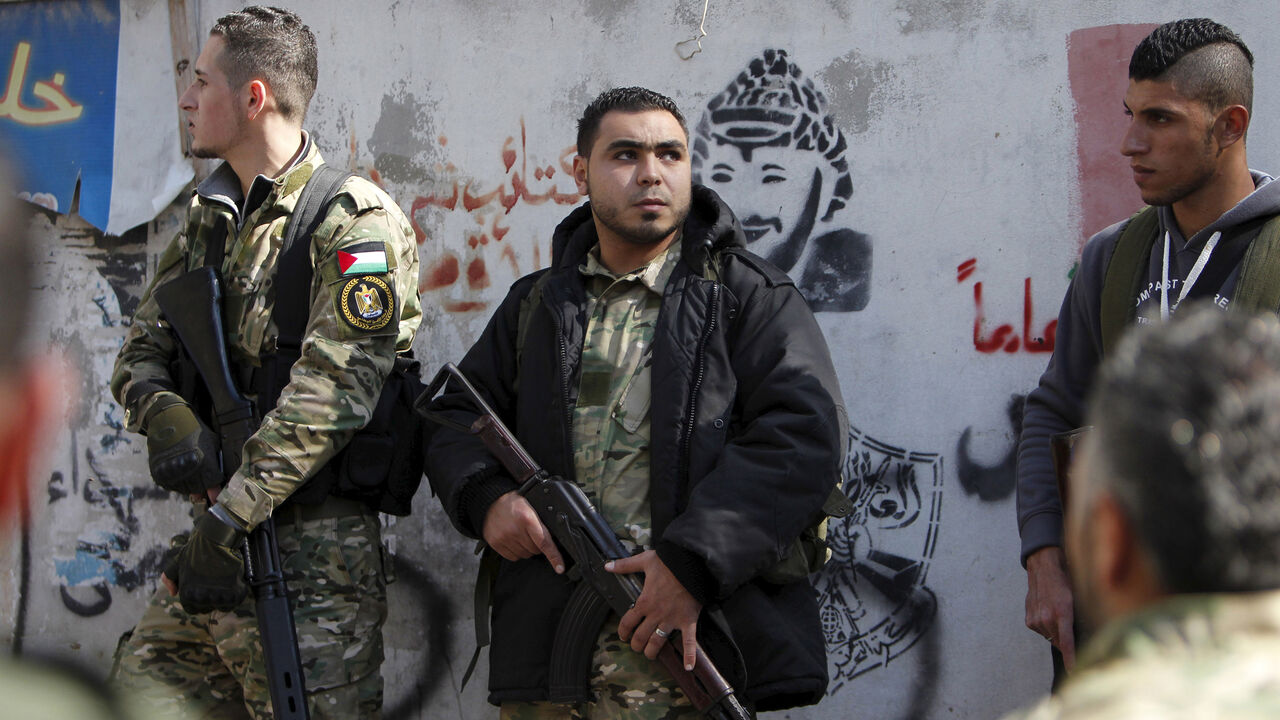 LEBANON-SECURITY/ Armed gunmen attend the funeral of Fathi Zaydan, a Fatah official responsible for the Palestinian camp of Mieh Mieh, after an explosion that killed him yesterday, during his funeral in Mieh Mieh Palestinian refugee camp, near the port-city of Sidon, Lebanon, April 13, 2016. The wall shows a graffiti of late Palestinian leader Yasser Arafat. REUTERS/Ali Hashisho - GF10000381452