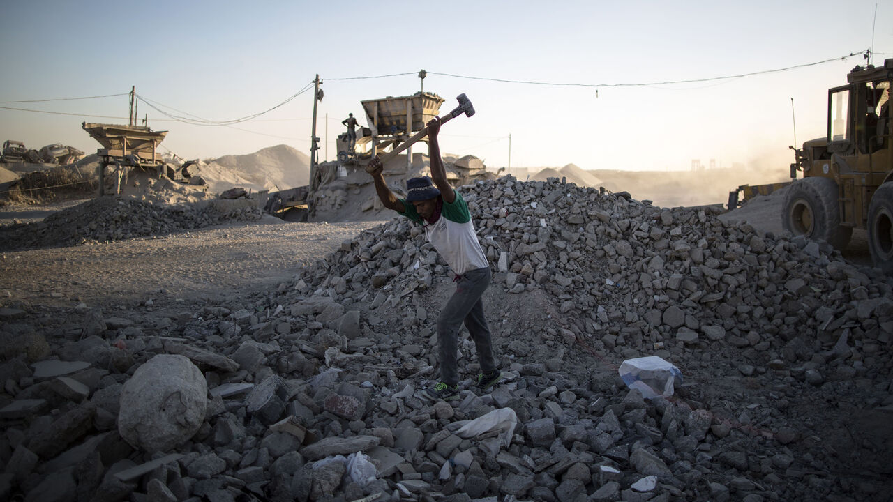 TOPSHOT - A Palestinian worker breaks stones at a factory where the rubble of houses, that were destroyed during wars, are recycled to be reused at construction sites on November 6, 2016 in Gaza City. / AFP / MAHMUD HAMS        (Photo credit should read MAHMUD HAMS/AFP/Getty Images)