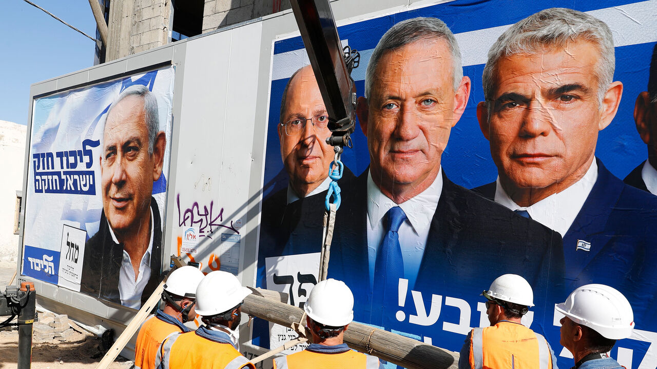 1134661969 Labourers work in front of electoral campaign posters bearing the portraits of Israel's Prime Minister Benjamin Netanyahu (L), leader of the Likud party, and retired Israeli general Benny Gantz (R), one of the leaders of the Blue and White (Kahol Lavan) political alliance, in the Israeli city of Tel Aviv, on April 3, 2019, ahead of the general election scheduled for April 9. (Photo by JACK GUEZ / AFP) (Photo credit should read JACK GUEZ/AFP/Getty Images)